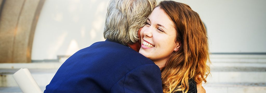 Una recién graduada le da un abrazo a su padre
