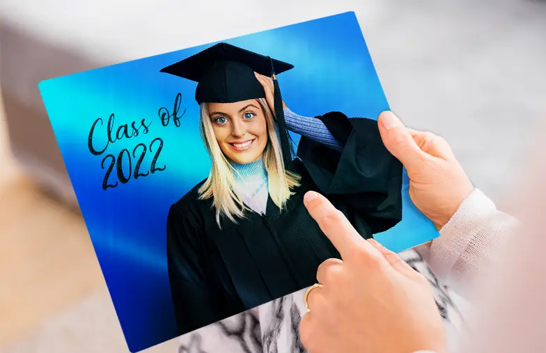 Impresión de Foto en Metal por Printerpix|Impresión de foto en aluminio de una graduación|Pequeña impresión metálica cuadrada de un hombre zambulléndose en un lago|Impresión de foto en metal de madre e hija en la estantería|Mujer colocando impresión metálica de novia y novio en la pared|Tres impresiones de fotos metálicas de tamaños variados|||||