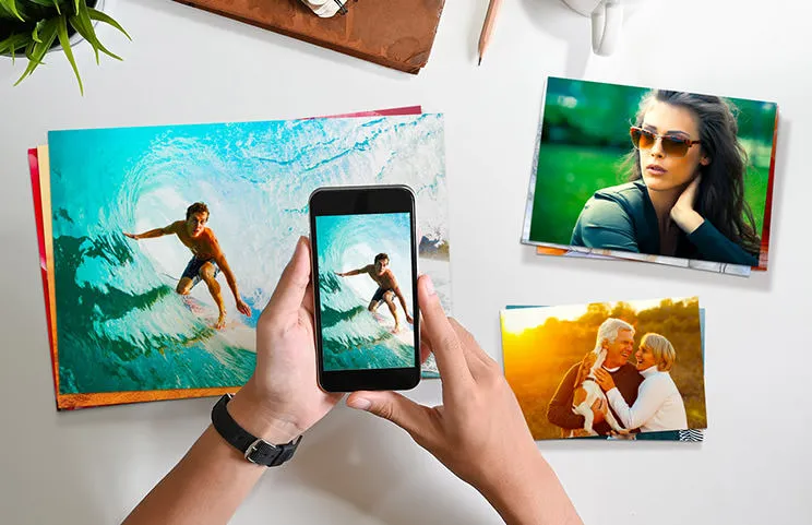 Impresiones fotográficas pequeñas, medianas y grandes en la mesa desde el teléfono móvil