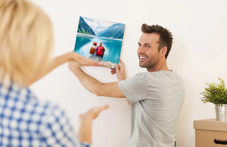 Hombre y mujer colocando un lienzo fotográfico con una foto de vacaciones