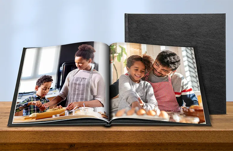 Álbum de fotos personalizado abierto en la mesa con collage de fotos familiares