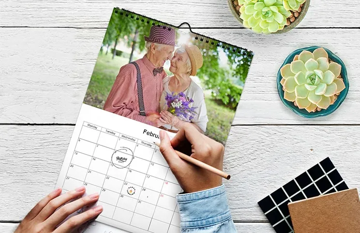 Mujer escribiendo en calendario de pared personalizado A4 de printerpix con foto de tema navideño