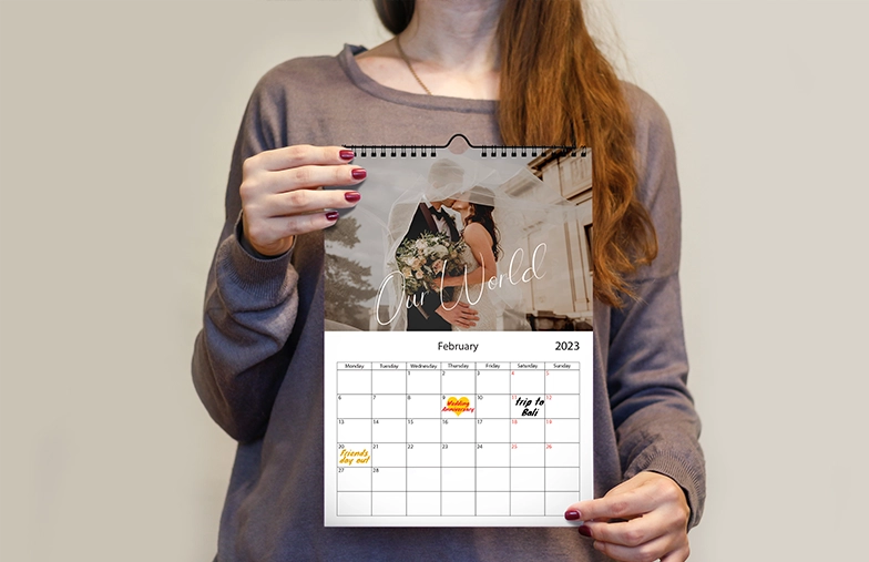 Mujer escribiendo en calendario de pared personalizado A4 de printerpix con foto de tema navideño
