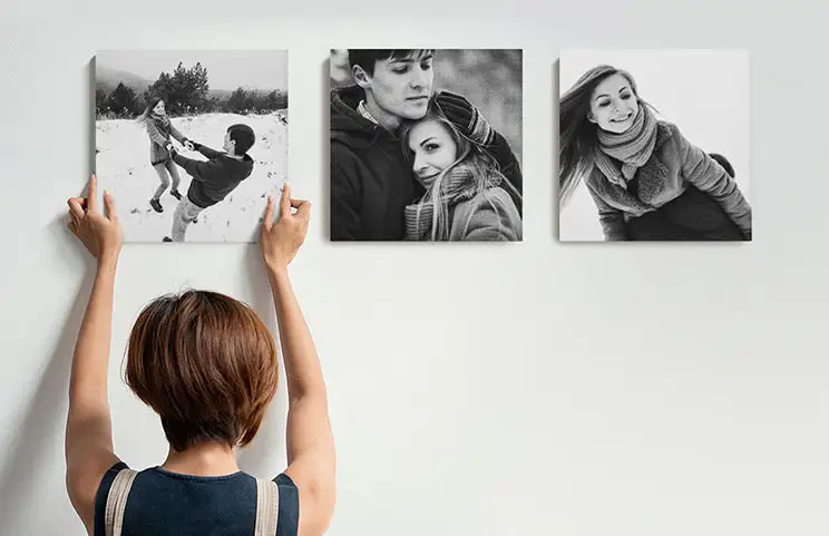 Mujer colocando tres lienzos fotográficos familiares en blanco y negro