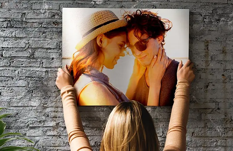 Mujer colocando impresión de metal de novia y novio en la pared