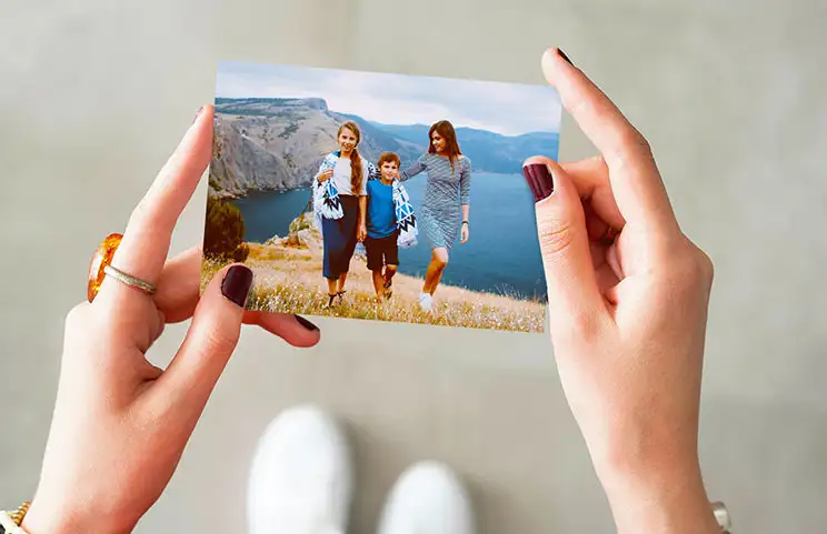 Manos sosteniendo una impresión fotográfica de tres niños de vacaciones