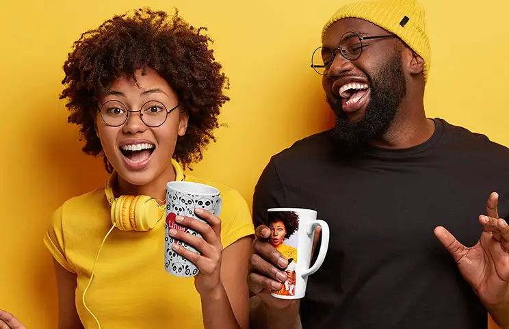 Pareja joven sosteniendo tazas de latte personalizadas con texto e imágenes