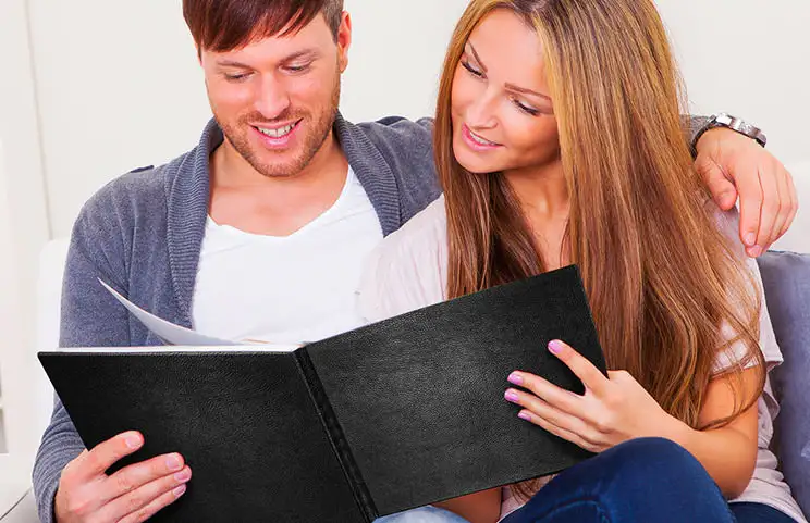 Pareja mira libro de fotos personalizado con cubierta de cuero hecho por Printerpix
