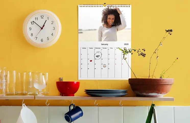 Pareja romántica en la sala de estar con calendario de pared 2020 personalizado con foto de propuesta